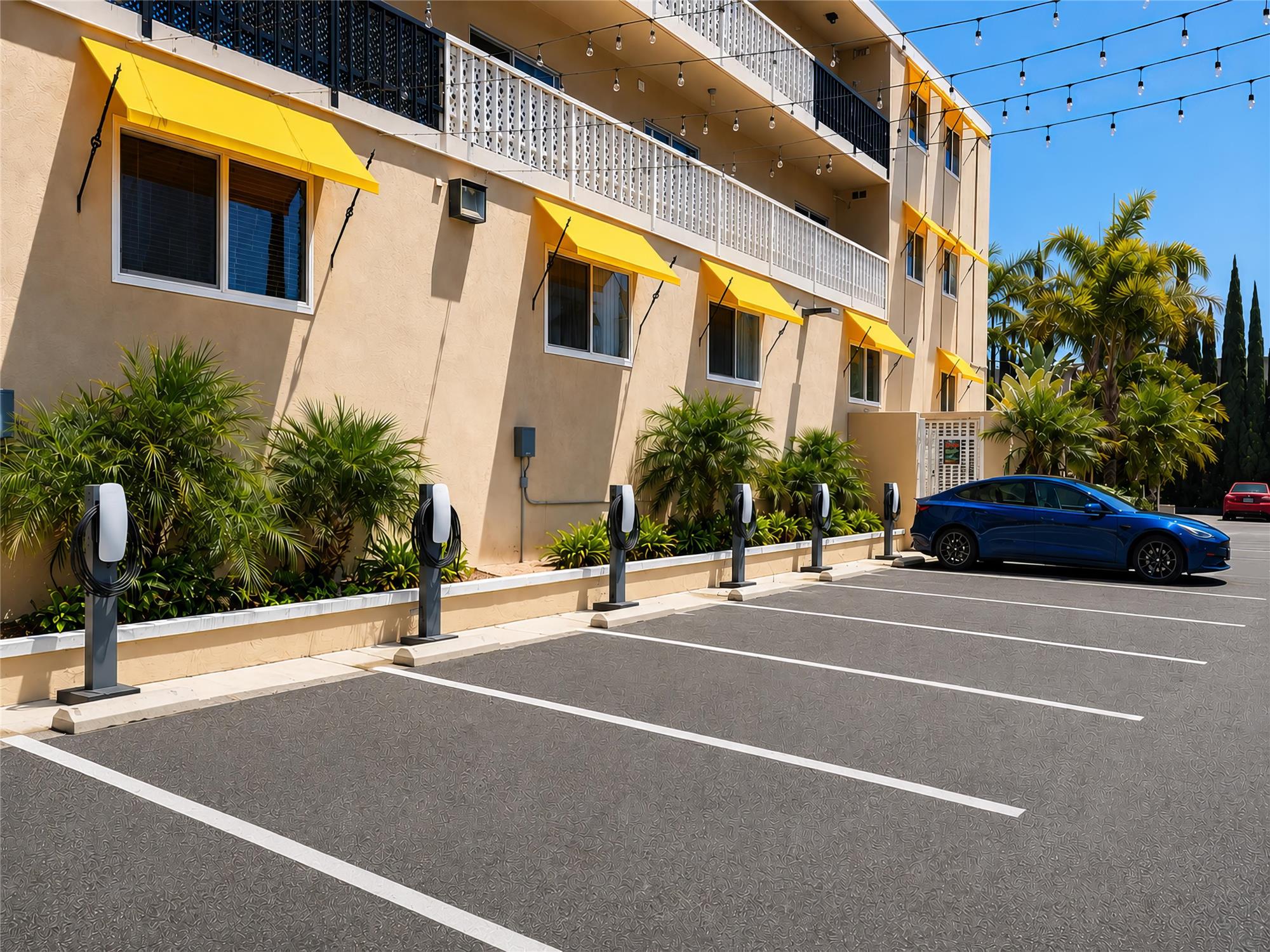 A beige building with yellow awnings and electric vehicle charging stations in the parking lot.