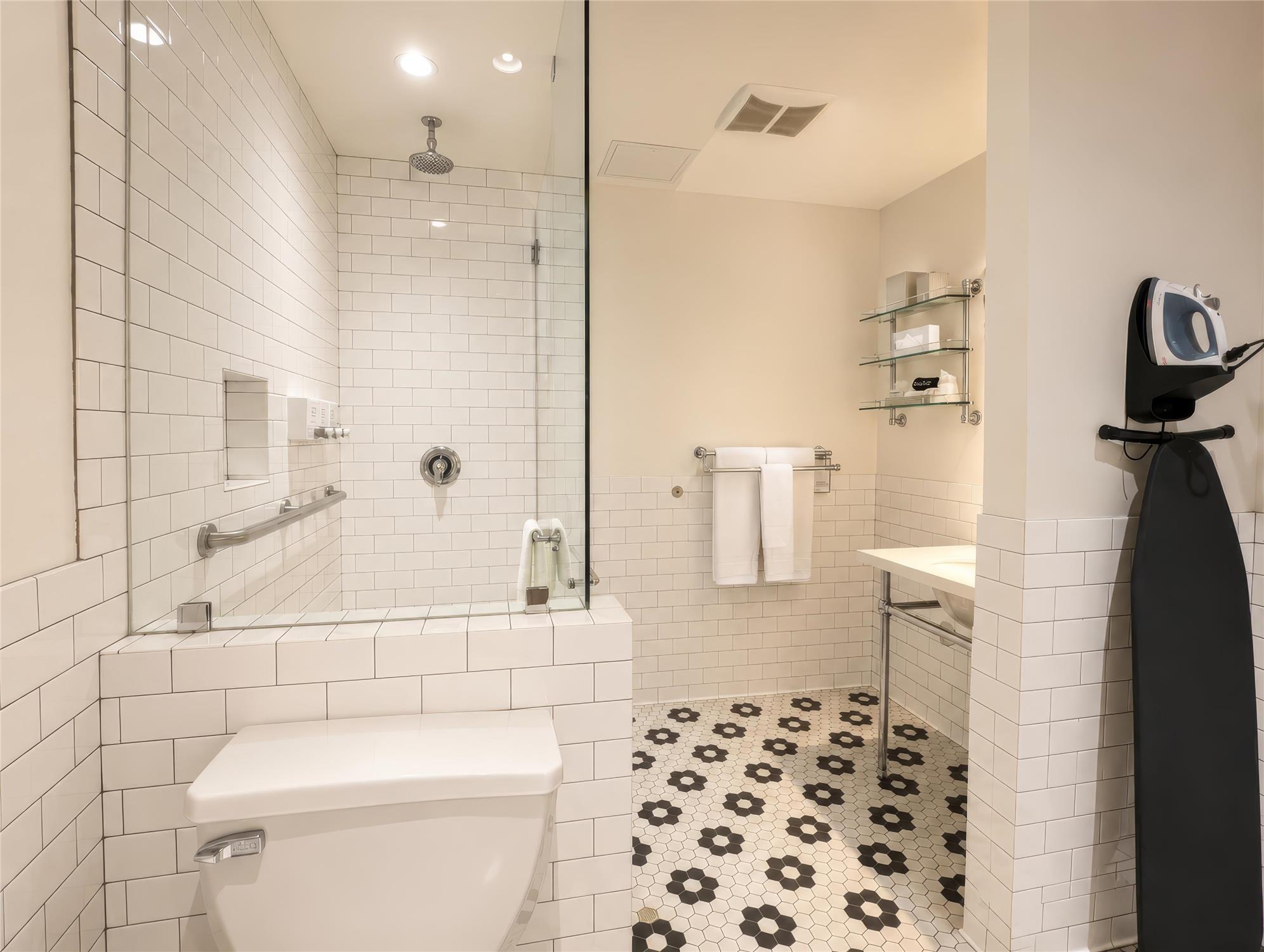 A clean bathroom with white tiled walls, a shower, toilet, and sink.