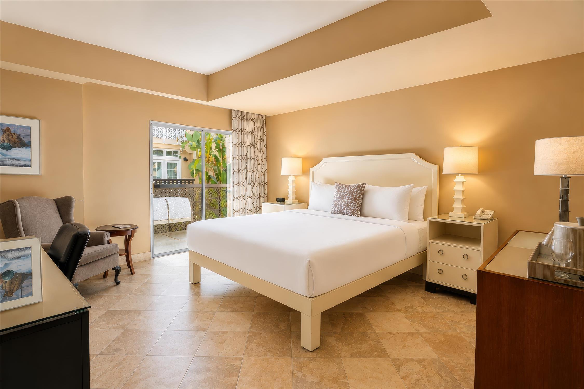 A hotel room with a large bed, nightstands, and a sitting area.